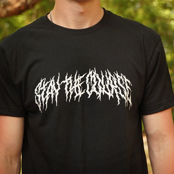 Person wearing a black T-shirt with "Stay the Course" printed in white in heavy metal style