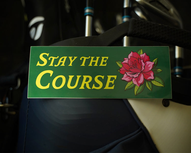 Green sticker with 'Stay the Course' and a flower on a dark background