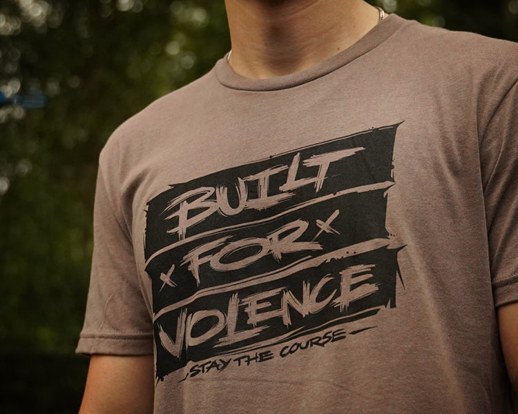Person wearing a t-shirt with 'Built for Violence' text design.
