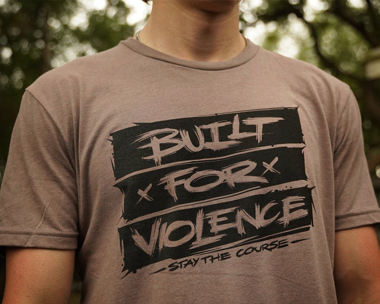 Person wearing a t-shirt with 'Built for Violence' text design.