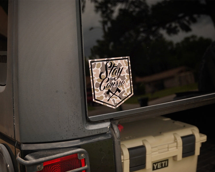 Duck camo decal on a vehicle window with 'Stay the Course' text, next to a YETI cooler.