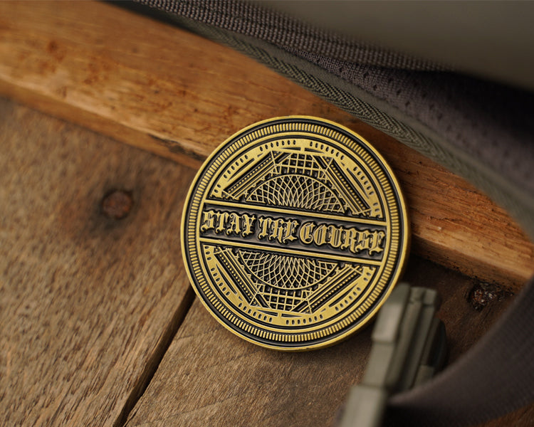 antique brass coin with 'Stay the Course' inscription on a wooden surface