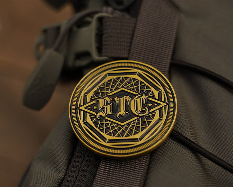 Close-up of a brass emblem with 'STC' on a brown bag.