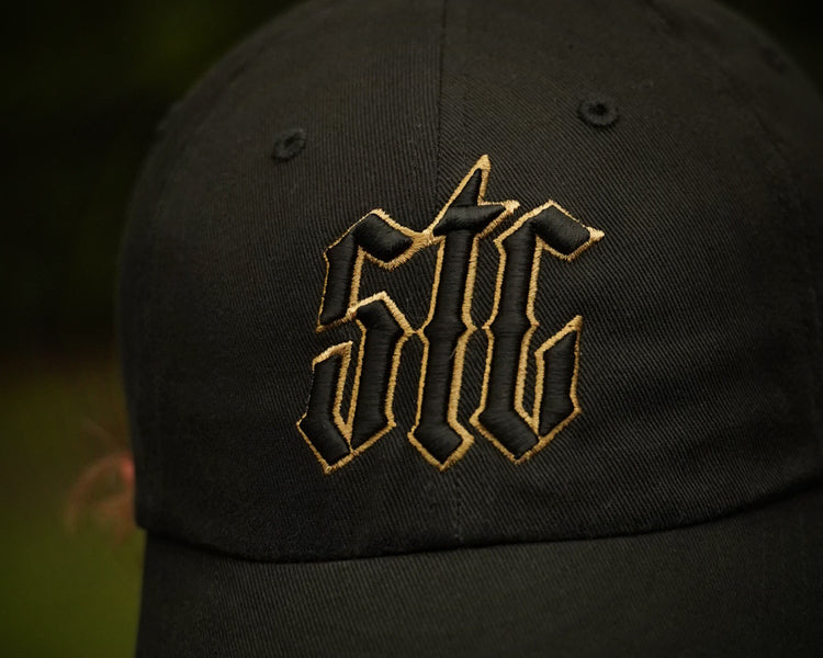 Black cap with gold logo on a blurred background