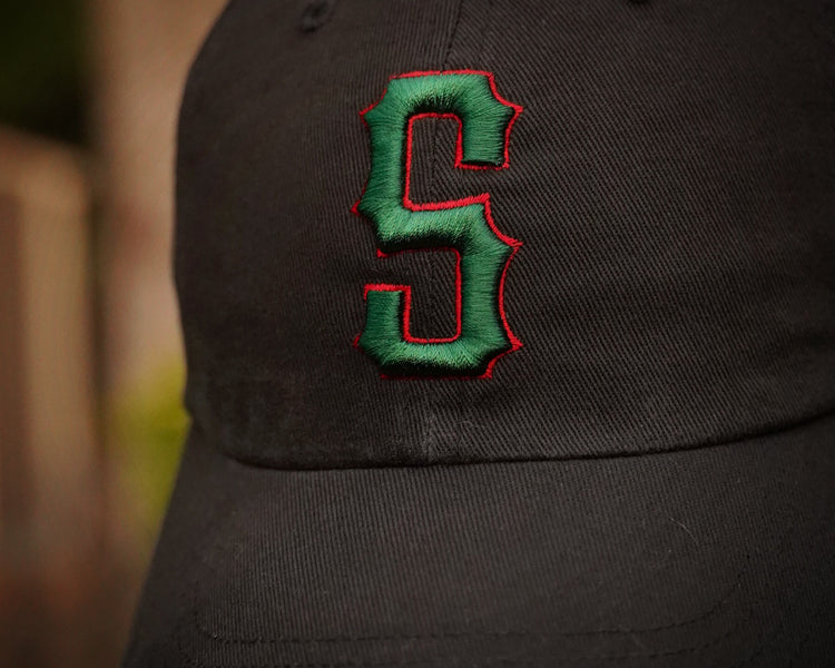 Black cap with a green and red 'S' logo on a blurred background