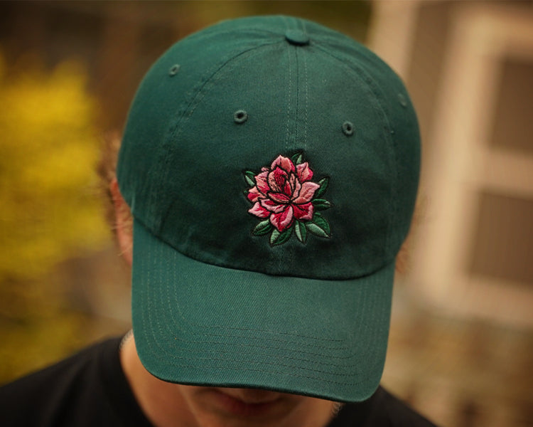 Green cap with a pink azalea embroidery on a blurred background