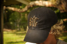 Black cap with gold and brown logo worn by a person outdoors