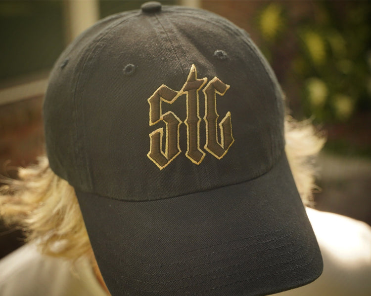 Black cap with gold and brown embroidery on a blurred background