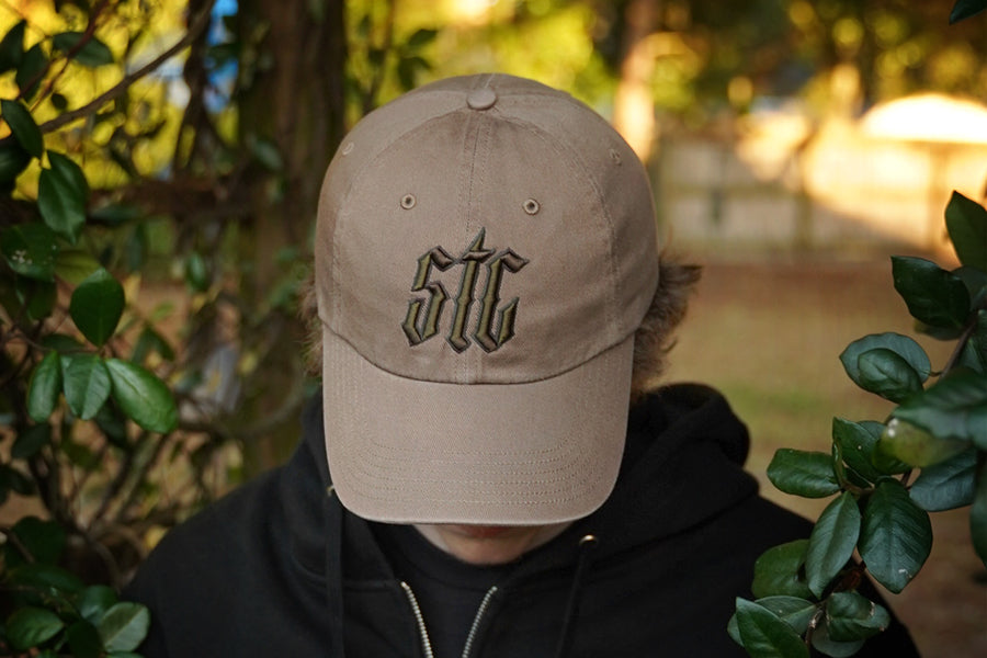Person wearing a beige cap with 'STC' logo outdoors