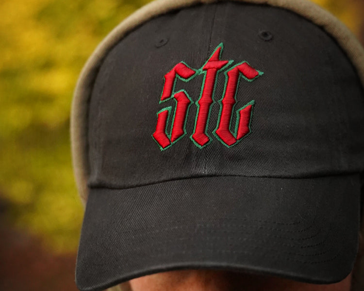 Black cap with red and green logo worn by a person, blurred background