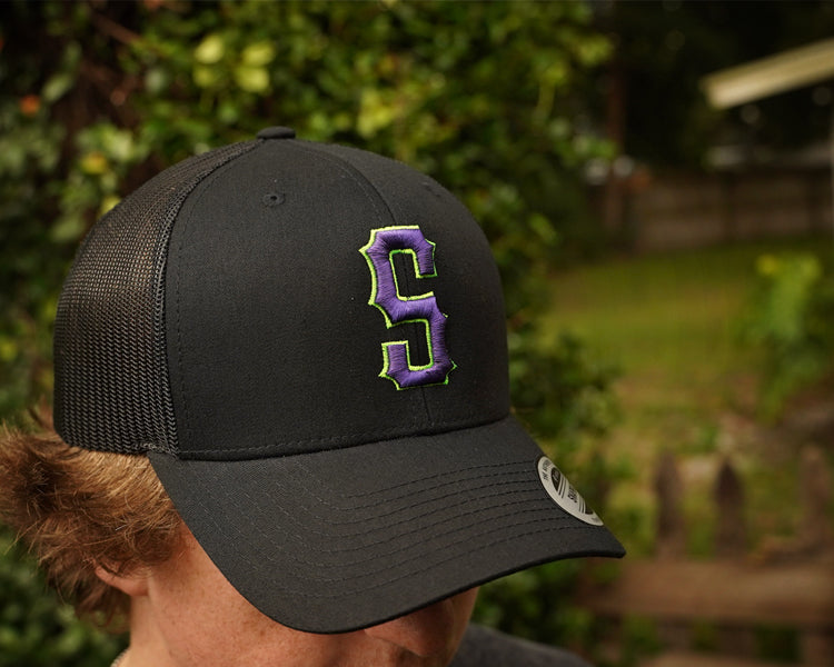 Person wearing a black cap with a purple logo outdoors