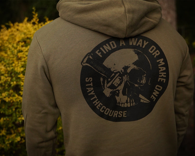 Person wearing a green hoodie with a skull and crossbones design on the back, featuring text.