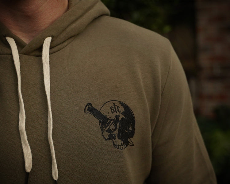 Green hoodie with a black skull design on the chest, blurred background
