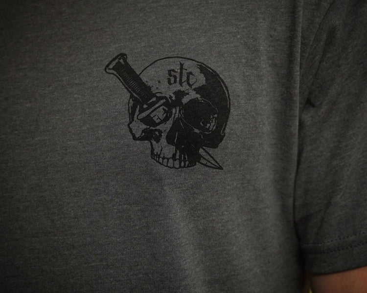 Person wearing a gray shirt with black graphic of a skull and dagger