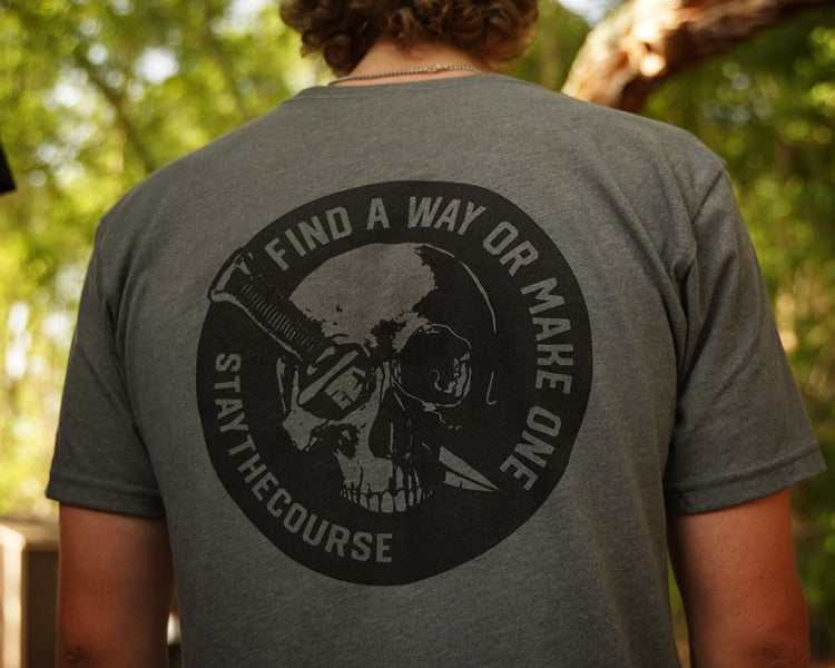 Person wearing a gray shirt with black graphic print that says "Find a way or make one - Stay the Course"