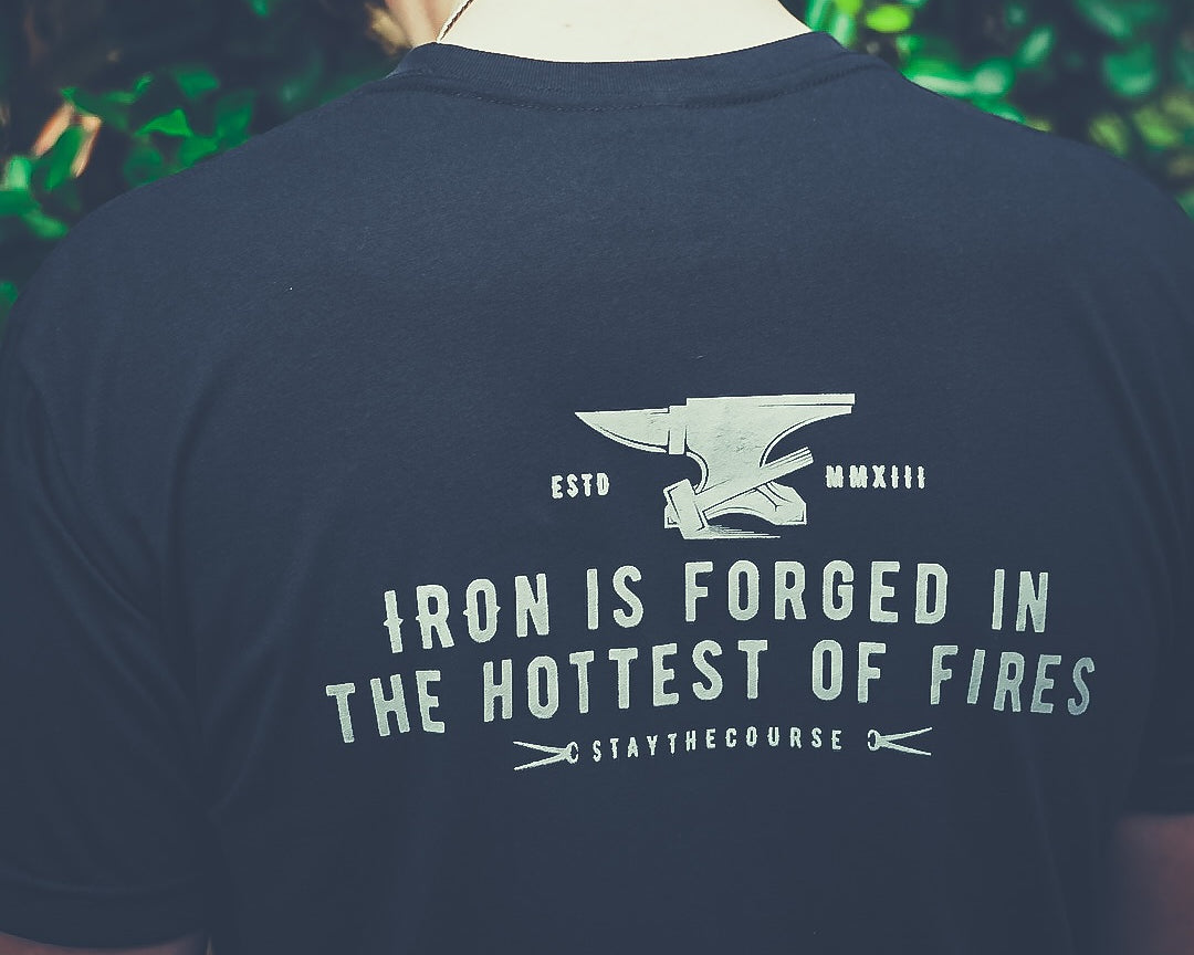 Person wearing a black t-shirt with a motivational quote and an anvil graphic.