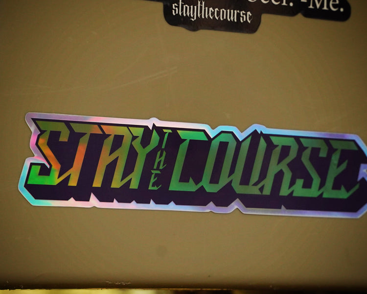 Holographic 'Stay the Course' sticker on a beige surface