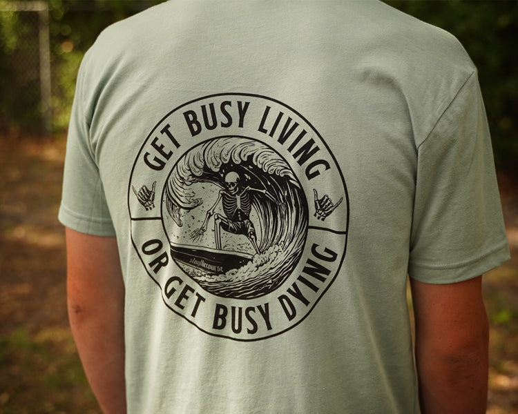 Person wearing a green shirt with black graphic that says "get busy living or get busy dying"