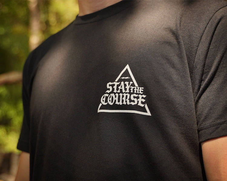 Person wearing a black t-shirt with 'Stay the Course' logo outdoors