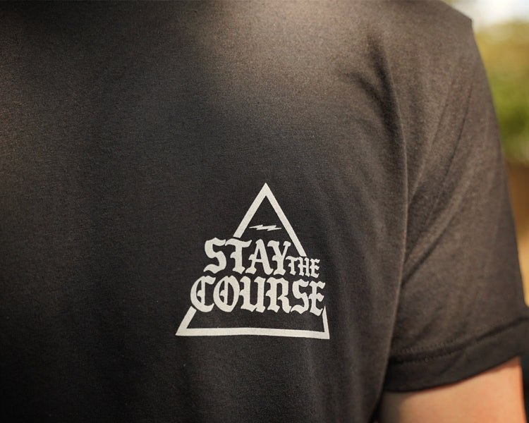 Black t-shirt with 'Stay the Course' triangle logo on the back, blurred background