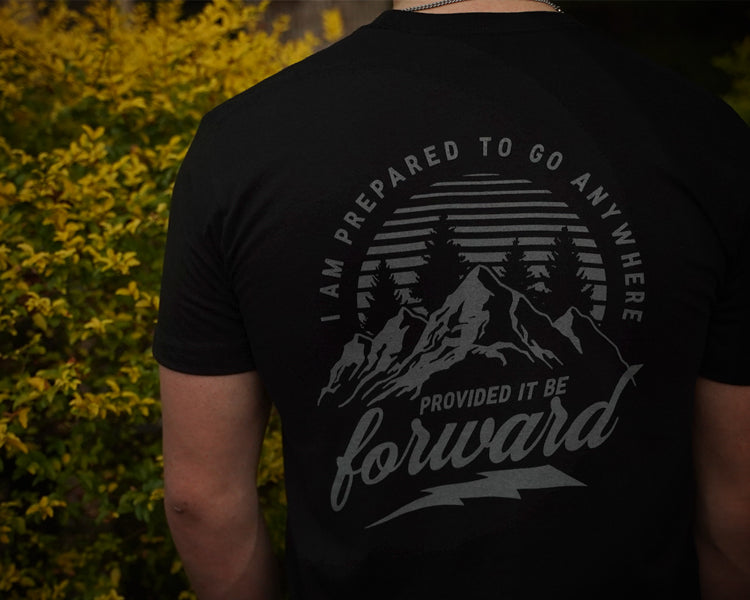 Person wearing a black t-shirt with a motivational quote and mountain graphic.