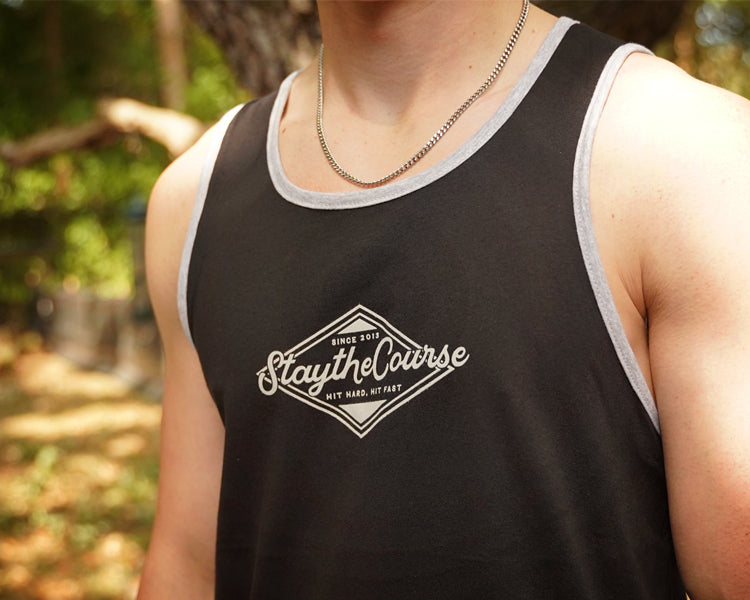 Person wearing a black tank top with 'Stay the Course' logo outdoors.
