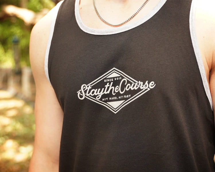 Person wearing a black tank top with 'Stay the Course' logo outdoors.