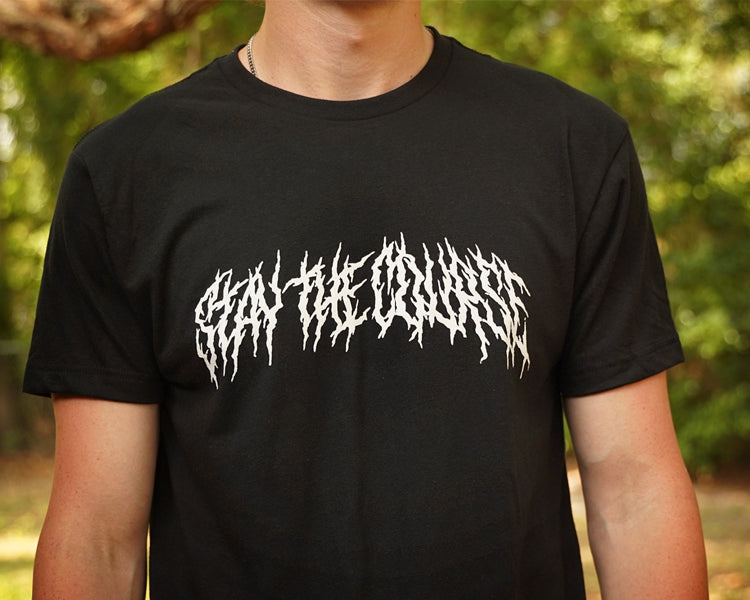 Person wearing a black T-shirt with "Stay the Course" printed in white in heavy metal style