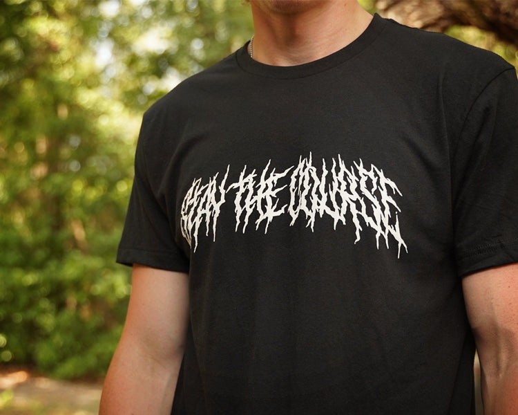Person wearing a black T-shirt with "Stay the Course" printed in white in heavy metal style