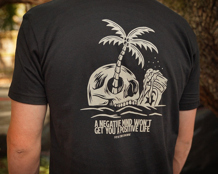 Black t-shirt with a skull and palm tree design on the back, featuring text.