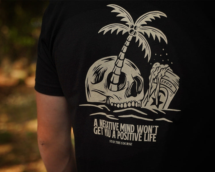 Black t-shirt with a white skull and palm tree design and motivational quote.