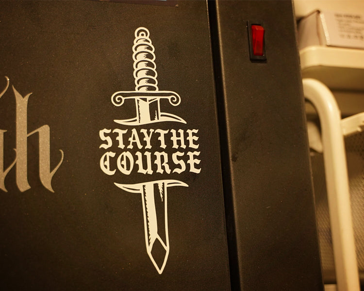White vinyl decal of dagger and "stay the course" on metal cabinet
