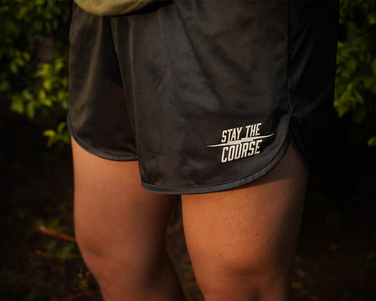 Black athletic shorts with 'Stay the Course' text on a person against a dark background