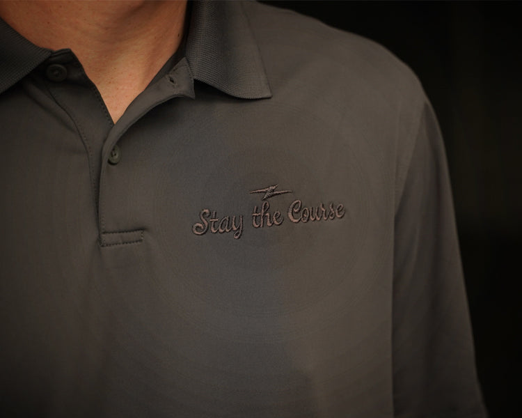 Dark gray polo shirt with 'Stay the Course' logo on a black background