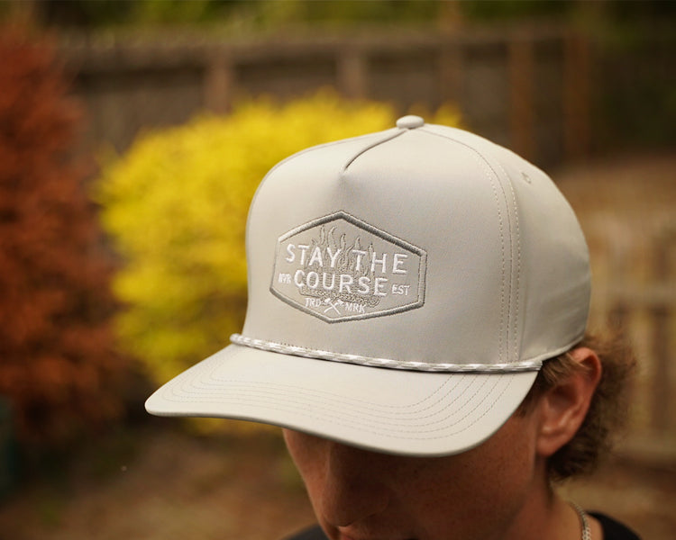 Person wearing a gray cap with 'Stay the Course' logo outdoors