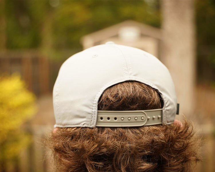 Person wearing a gray cap with a blurred outdoor background