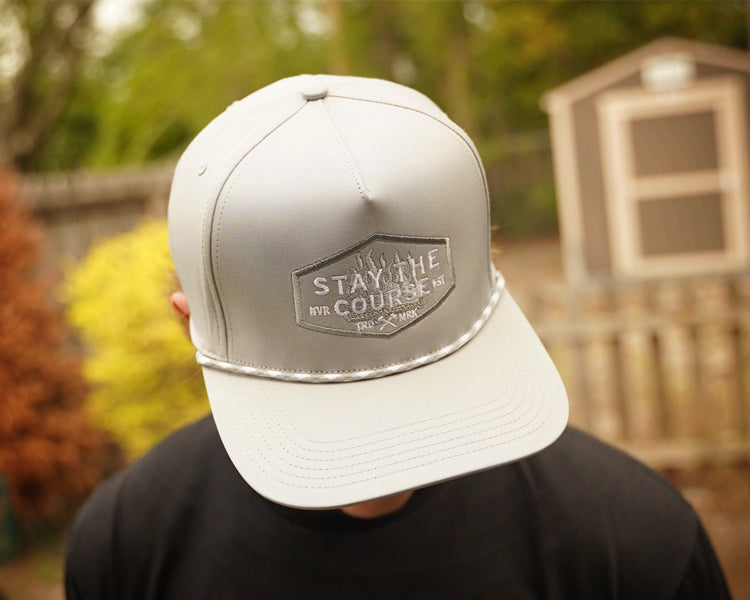Person wearing a gray cap with a logo and text, outdoors.
