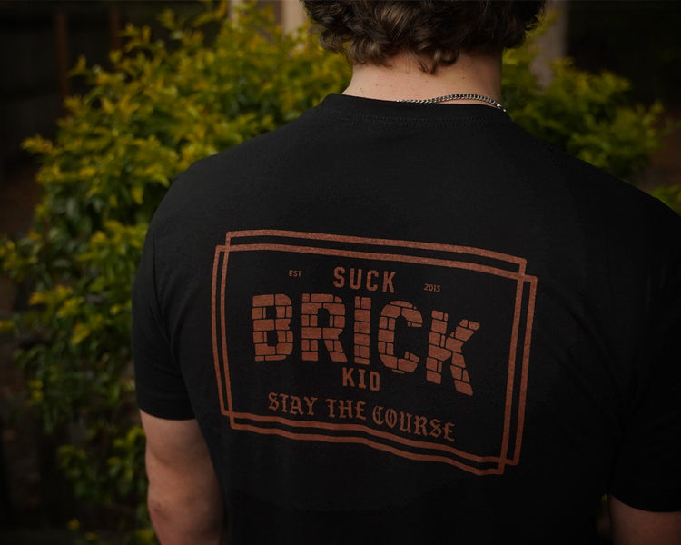 Person wearing a black t-shirt with text on the back, standing outdoors.