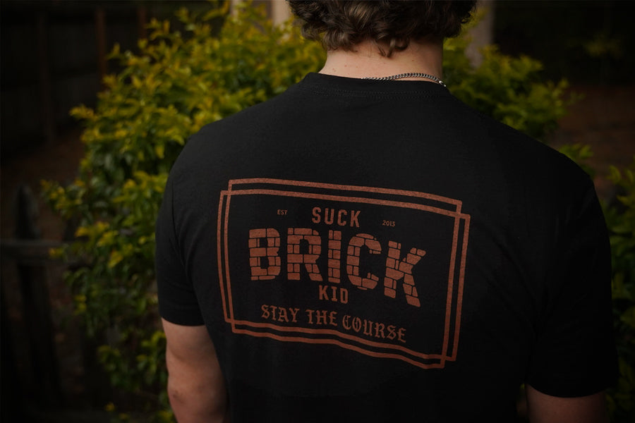 Person wearing a black t-shirt with text on the back, standing outdoors.