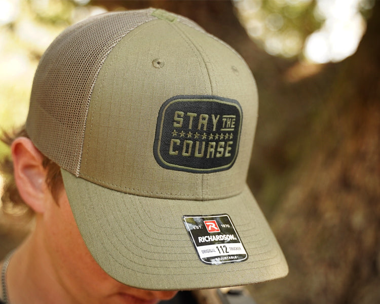 Olive green cap with 'Stay the Course' text and Richardson logo on a blurred natural background