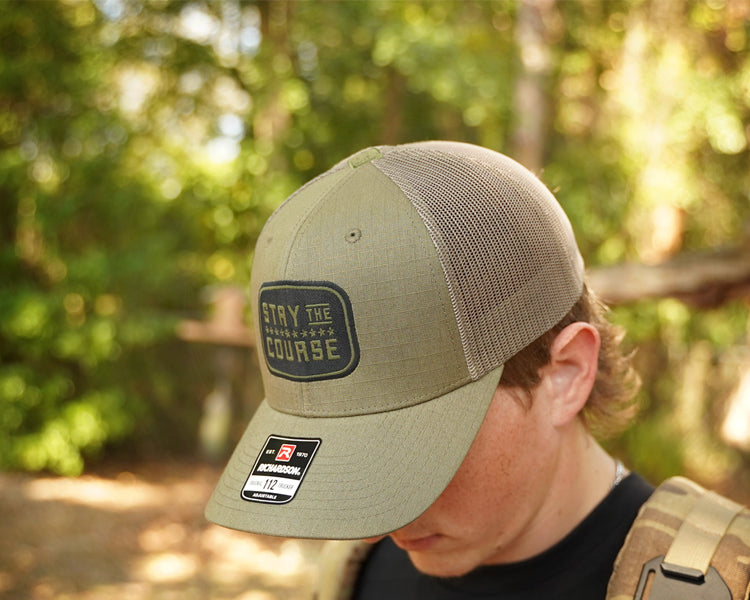 Person wearing a green cap with a logo and text in a forest setting