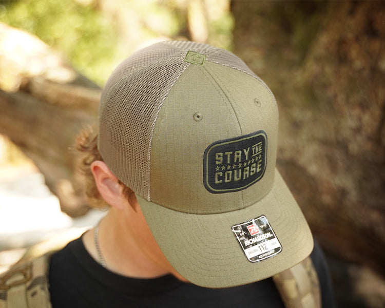 Person wearing a cap with 'Stay the Course' logo in a natural setting