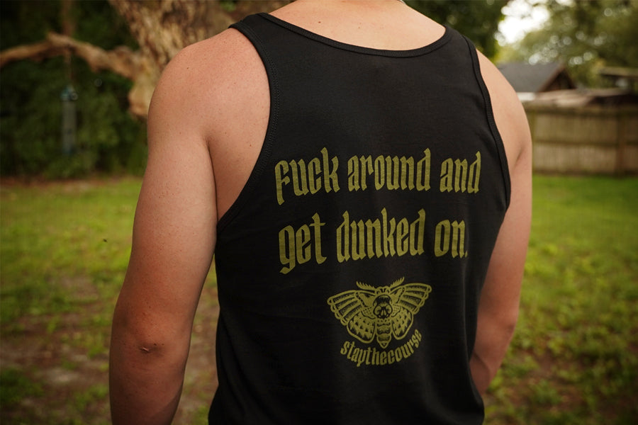 Person wearing a black tank top with green text and logo outdoors