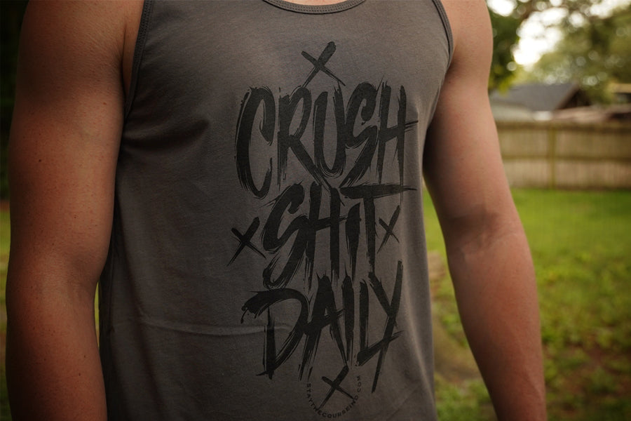 Person wearing a tank top with 'CRUSH SHIT DAILY' text in an outdoor setting