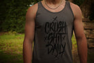 Person wearing a tank top with 'CRUSH SHIT DAILY' text outdoors.
