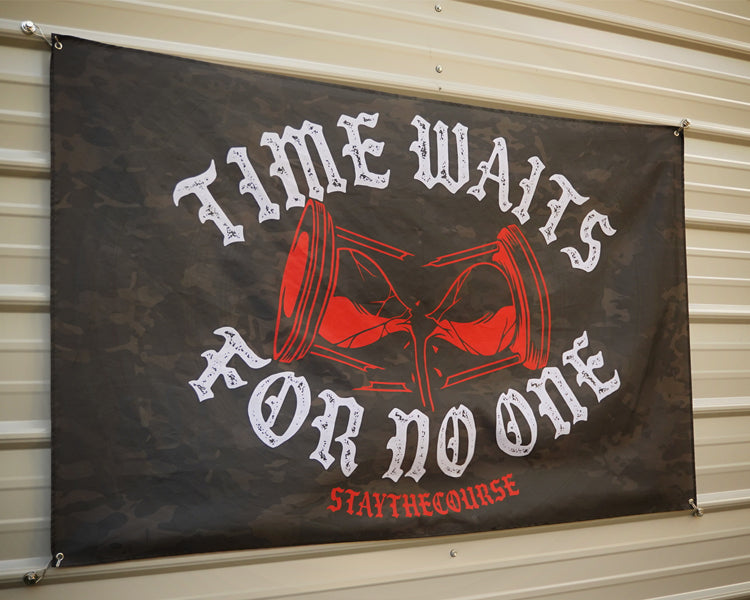 5x3 black camo flag with white and red design that says ice waits for no one, hanging on a metal siding building