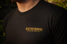 Black t-shirt with 'STAYTHECOURSE' logo on a blurred background