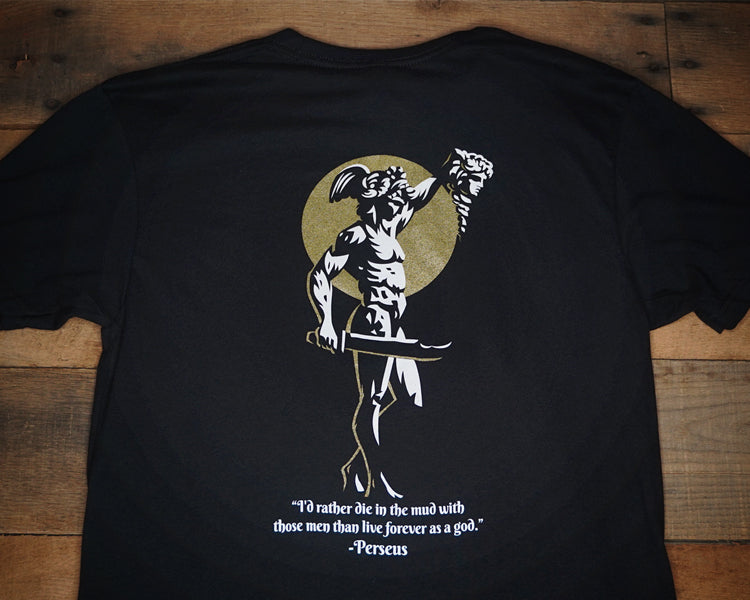Black T-shirt with white and gold print featuring a character and text on the back, with a small front left chest print.