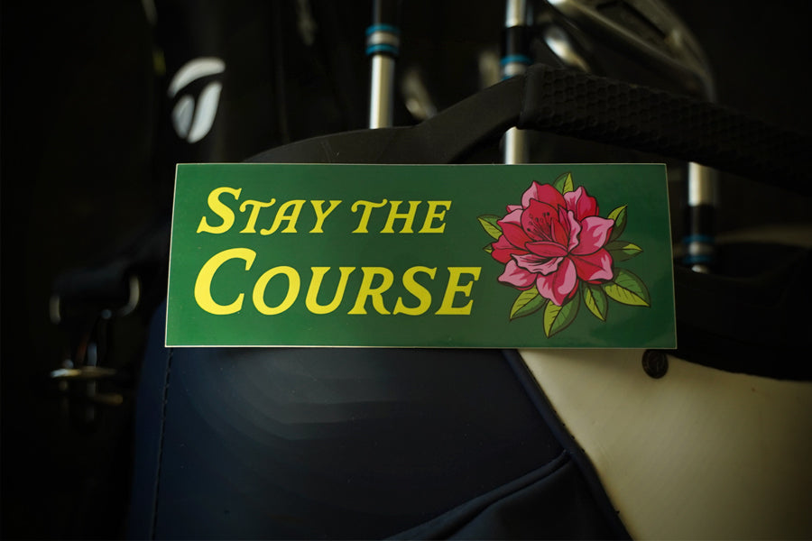 Green sticker with 'Stay the Course' and a flower on a dark background