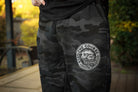 Camouflage pants with a logo on a blurred outdoor background
